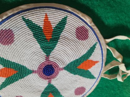 Round beaded rosette purse on white hide with fringe and tie handles, plate 86