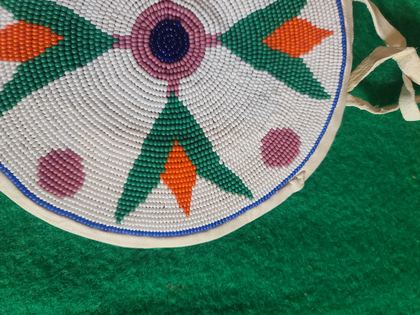 Round beaded rosette purse on white hide with fringe and tie handles, plate 87